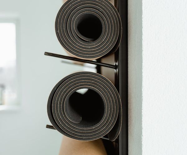 A clean, bright yoga studio with rolled mats and large windows.