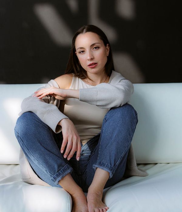 Woman in a calm, seated yoga pose in a bright, minimalist room.